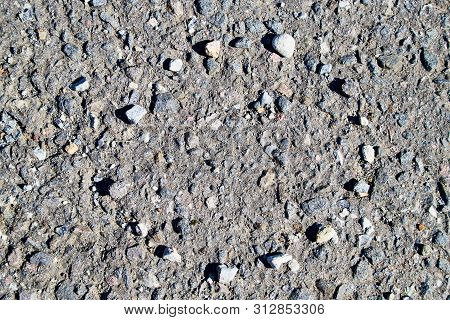 Stone Asphalt Texture Of Road And Pebbles Circle. Grey Asphalt Road And And A Hand-made Circle Of Gr