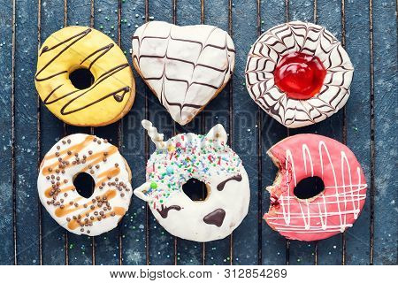 Frosted Donuts With Bite Missing On Dark Background.
