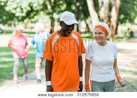 Selective Focus Of African American Senior Man And Cheerful Retired Woman Smiling Near Pensioners Ou