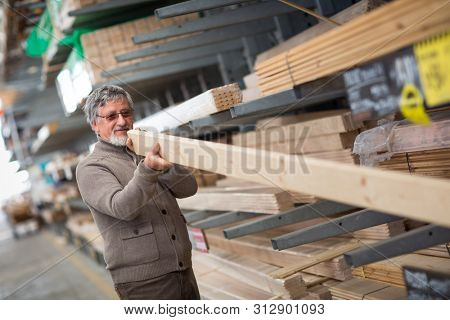 Man choosing and buying construction wood in a DIY store for his DIY home re-modeling project