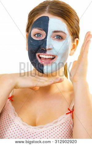 Woman With Clay Carbo Black Mask On Half Face And White Mud On Second Half. Girl Taking Care Of Oily