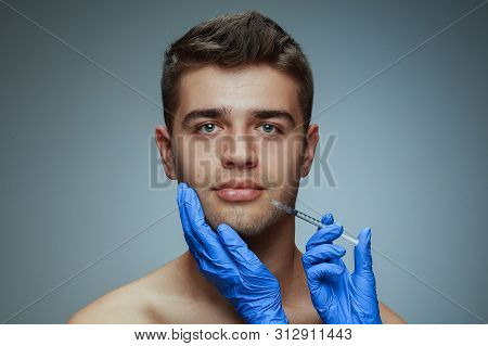Close-up Portrait Of Young Man Isolated On Grey Studio Background. Filling Surgery Procedure. Concep