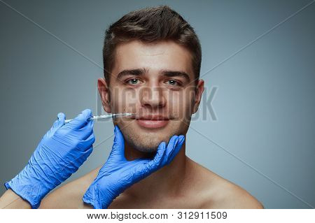 Close-up Portrait Of Young Man Isolated On Grey Studio Background. Filling Surgery Procedure. Concep