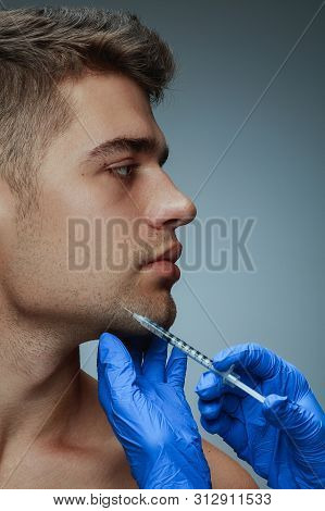 Close-up Portrait Of Young Man Isolated On Grey Studio Background. Filling Surgery Procedure. Concep