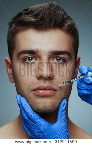 Close-up Portrait Of Young Man Isolated On Grey Studio Background. Filling Surgery Procedure. Concep