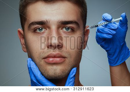 Close-up Portrait Of Young Man Isolated On Grey Studio Background. Filling Surgery Procedure. Concep