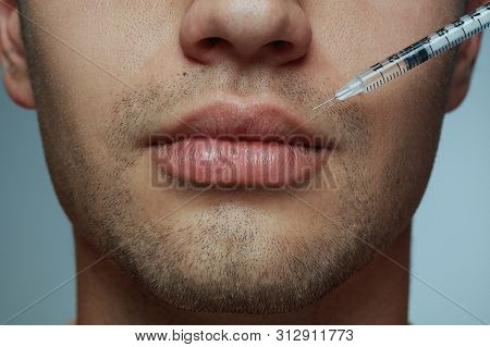 Close-up Portrait Of Young Man Isolated On Grey Studio Background. Filling Surgery Procedure. Concep