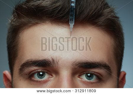 Close-up Portrait Of Young Man Isolated On Grey Studio Background. Filling Surgery Procedure. Concep