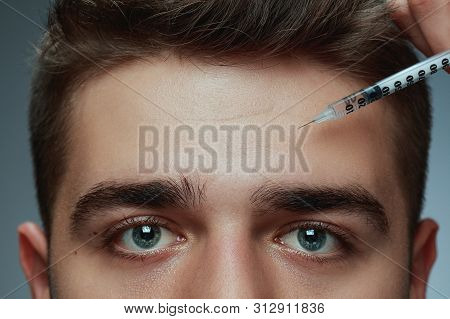 Close-up Portrait Of Young Man Isolated On Grey Studio Background. Filling Surgery Procedure. Concep