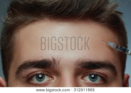 Close-up Portrait Of Young Man Isolated On Grey Studio Background. Filling Surgery Procedure. Concep
