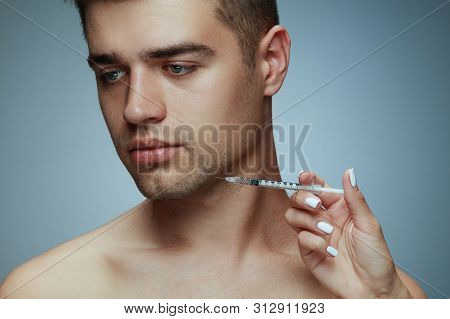 Close-up Portrait Of Young Man Isolated On Grey Studio Background. Filling Surgery Procedure. Concep