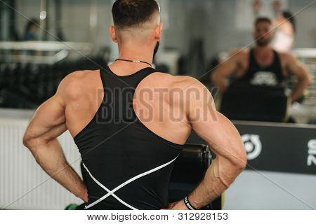 A Young Athlete Trains In The Gym. Trians Biceps Muscules