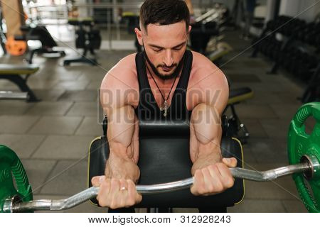 A Young Athlete Trains In The Gym. Trians Biceps Muscules
