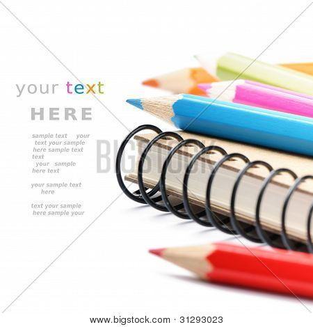 Lápices de colores y Notebook aislado en blanco