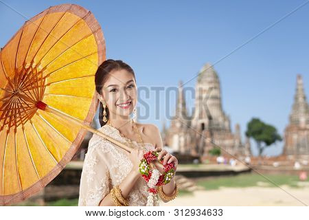 Thai Asian Women Welcome With Traditional Thai Suit And Umbrella On Temple Background, Hello Sawadee