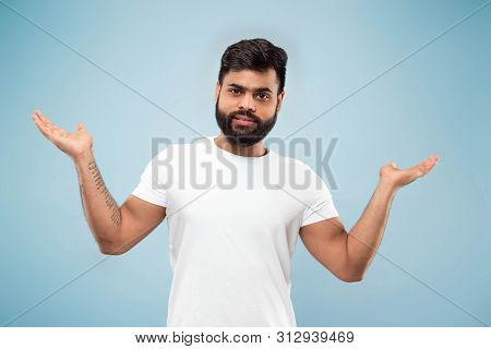 Half-length Close Up Portrait Of Young Hindoo Man In White Shirt On Blue Background. Human Emotions,