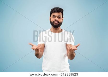 Half-length Close Up Portrait Of Young Hindoo Man In White Shirt On Blue Background. Human Emotions,