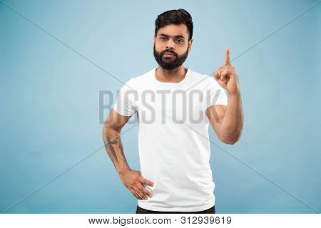 Half-length Close Up Portrait Of Young Hindoo Man In White Shirt On Blue Background. Human Emotions,