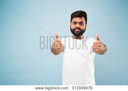 Half-length Close Up Portrait Of Young Hindoo Man In White Shirt On Blue Background. Human Emotions,