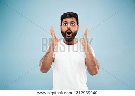 Half-length Close Up Portrait Of Young Hindoo Man In White Shirt On Blue Background. Human Emotions,