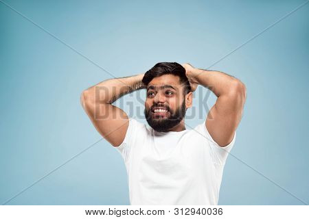 Half-length Close Up Portrait Of Young Hindoo Man In White Shirt On Blue Background. Human Emotions,