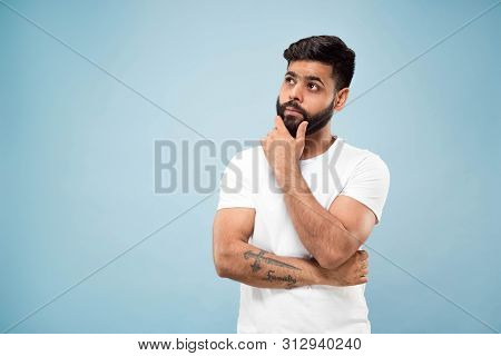 Half-length Close Up Portrait Of Young Hindoo Man In White Shirt On Blue Background. Human Emotions,