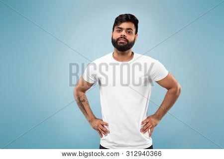 Half-length Close Up Portrait Of Young Hindoo Man In White Shirt On Blue Background. Human Emotions,