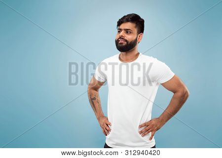 Half-length Close Up Portrait Of Young Hindoo Man In White Shirt On Blue Background. Human Emotions,