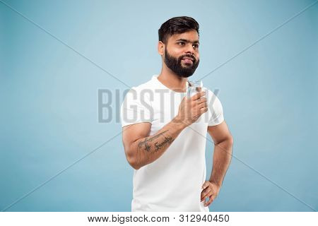 Half-length Close Up Portrait Of Young Hindoo Man In White Shirt On Blue Background. Human Emotions,