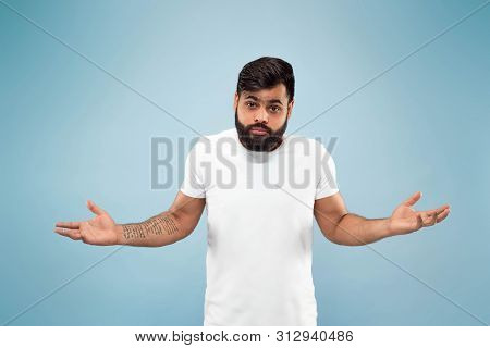 Half-length Close Up Portrait Of Young Hindoo Man In White Shirt On Blue Background. Human Emotions,