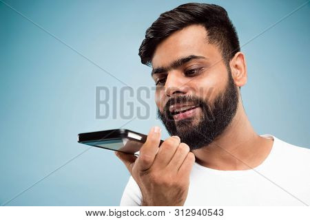 Half-length Close Up Portrait Of Young Hindoo Man In White Shirt On Blue Background. Human Emotions,