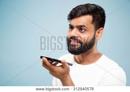 Half-length Close Up Portrait Of Young Hindoo Man In White Shirt On Blue Background. Human Emotions,