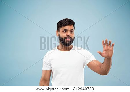 Half-length Close Up Portrait Of Young Hindoo Man In White Shirt On Blue Background. Human Emotions,