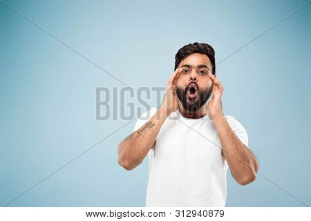 Half-length Close Up Portrait Of Young Hindoo Man In White Shirt On Blue Background. Human Emotions,