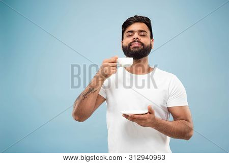 Half-length Close Up Portrait Of Young Hindoo Man In White Shirt On Blue Background. Human Emotions,