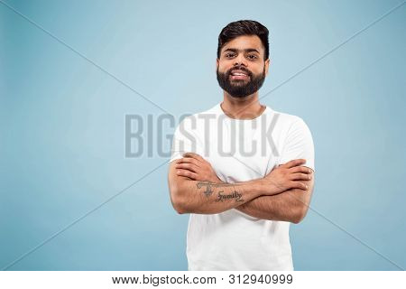 Half-length Close Up Portrait Of Young Hindoo Man In White Shirt On Blue Background. Human Emotions,