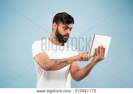Half-length Close Up Portrait Of Young Hindoo Man In White Shirt On Blue Background. Human Emotions,
