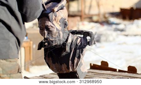 Man Holds Old Bust. Stock Footage. Man In Work Gloves Raises Dusty Old Bust Of Important Man Made Of