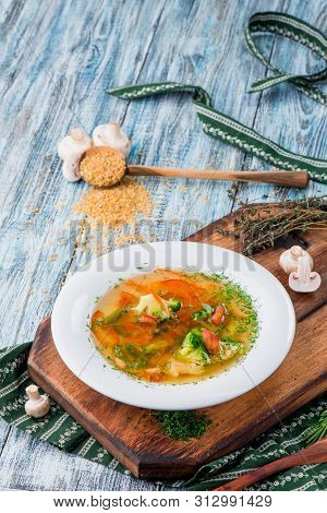 Vegetable Brot, Soup With Broccoli, Asparagus, Carrots, Onions, Bell Peppers And Greens In A White P