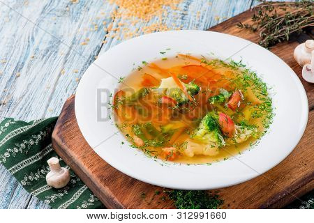 Vegetable Brot, Soup With Broccoli, Asparagus, Carrots, Onions, Bell Peppers And Greens In A White P