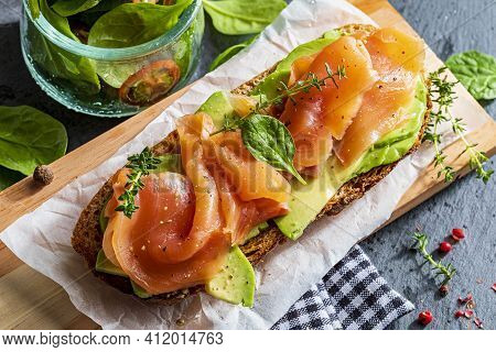 Appetizing And Healthy Smoked Salmon With Avocado And Vegetables (spinach Sprouts, Tomatoes, Thyme) 
