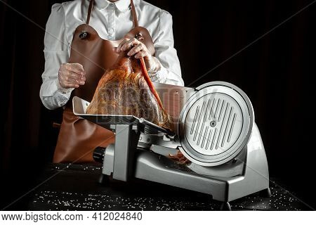 Slicing Hamon On Cutting Machine. Iberian Ham Cutter On Black Background.