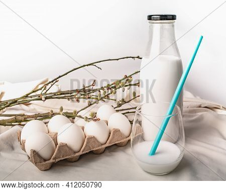 Chicken Eggs In An Egg Box, Willow Branches, A Bottle Of Milk And A Glass Of Milk With A Blue Straw 