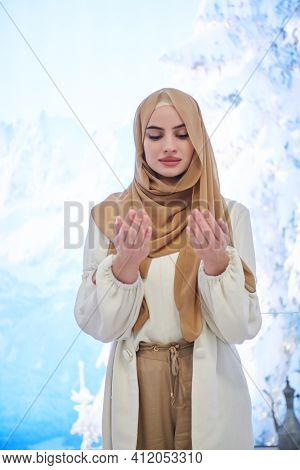 Portrait of young muslim woman praying or making dua to God
