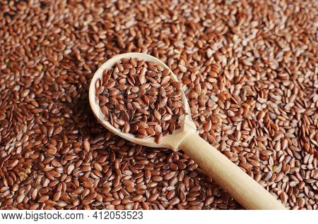 Uncooked Raw Flax Seeds In Wooden Spoon On Seeds Background.