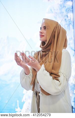 Portrait of young muslim woman praying or making dua to God