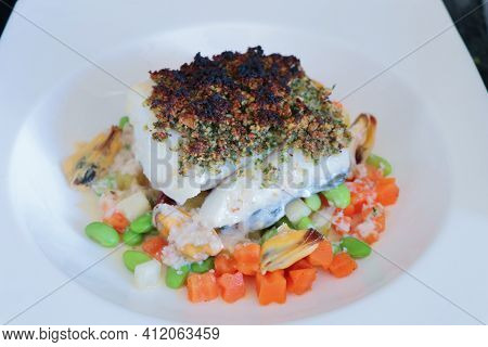 Close Up Of Steamed Fillet Of Fish And Mussels With Mixed Vegetables And White Sauce For Dinner Or L
