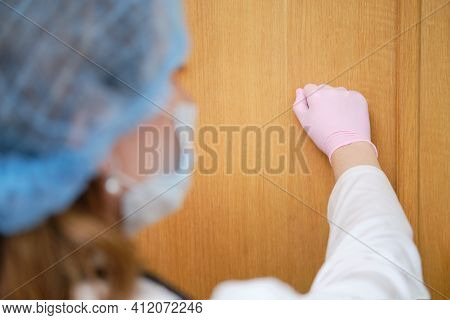 Doctor In Medical Mask Knocks On The Wooden Door