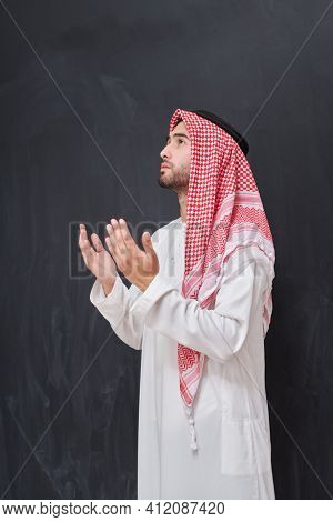 Arab man in traditional clothes praying to God or making dua