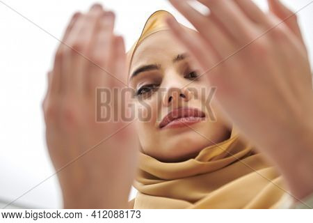 Portrait of young muslim woman making dua, praying to God